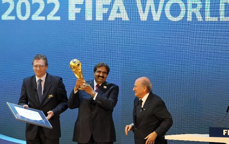 Qatar's Emir Sheikh Hamad bin Khalifa al-Thani (C) holds the World Cup trophy next to FIFA president Joseph Blatter (R) after Qatar was chosen to host the 2022 World Cup at the FIFA headquarters in Zurich on December 2, 2010. Qatar became the first Arab, Middle Eastern or Muslim country to be awarded the right to stage football's World Cup. AFP PHOTO/KARIM JAAFAR