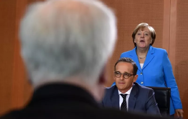 German Chancellor Angela Merkel (R) stands next to German Foreign Minister Heiko Maas and looks at Interior Minister Horst Seehofer (L) as they arrive for the weekly cabinet meeting in Berlin on June 13, 2018. / AFP PHOTO / Tobias SCHWARZ