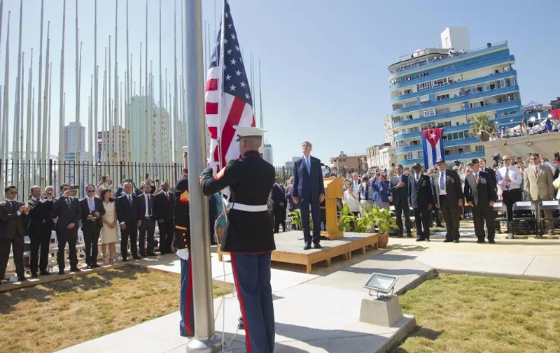 US Secretary of State John Kerry(C), stands with other dignitaries as members of the US Marines raise the US flag over the newly reopened embassy in Havana, Cuba on August 14, 2015. Kerry is at the Cuban capital to raise the US flag and formally reopen the long-closed US Embassy. Cuba and the US officially restored diplomatic relations July 20, as part of efforts to normalize ties between the former Cold War foes. AFP PHOTO/POOL/PABLO MARTINEZ MONSIVAIS