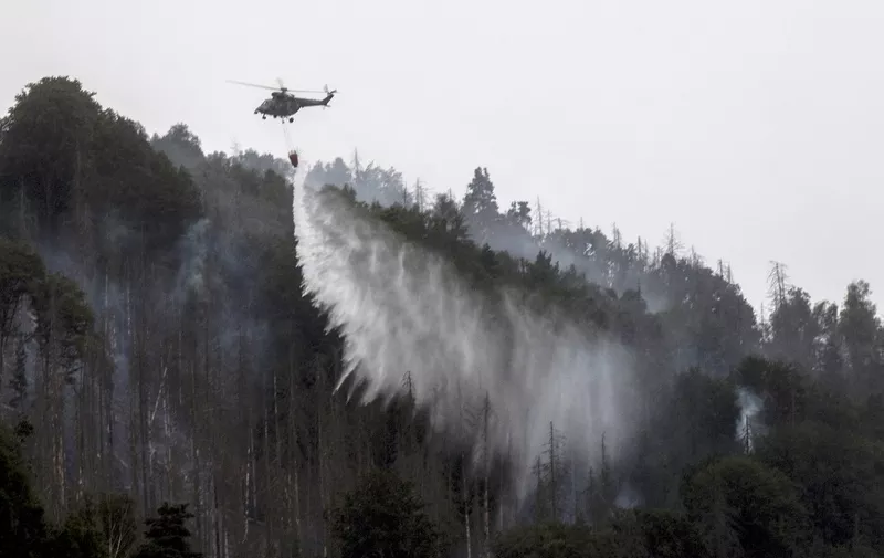 A helicopter drops water in order to contain a wildfire as it continues to burn in a forest near the town of Schmilka, eastern Germany, on July 27, 2022, near the border with the Czech Republic. (Photo by Michal Cizek / AFP)