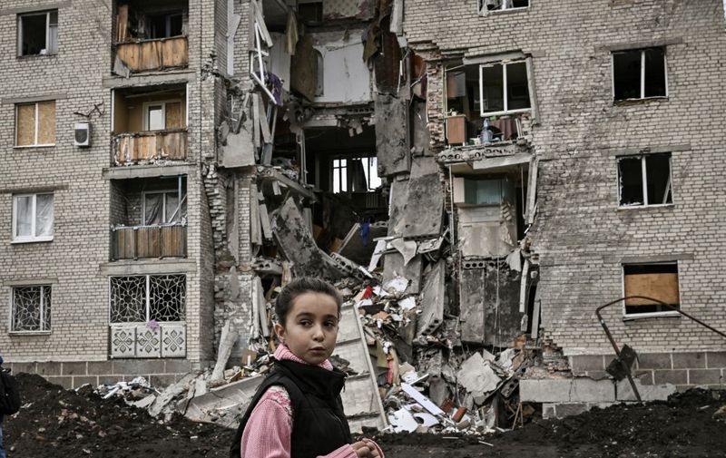 A young girl passes by a destroyed apartment building in Bakhmut in the eastern Ukranian region of Donbas on May 22, 2022, amid Russian invasion of Ukraine. (Photo by ARIS MESSINIS / AFP)