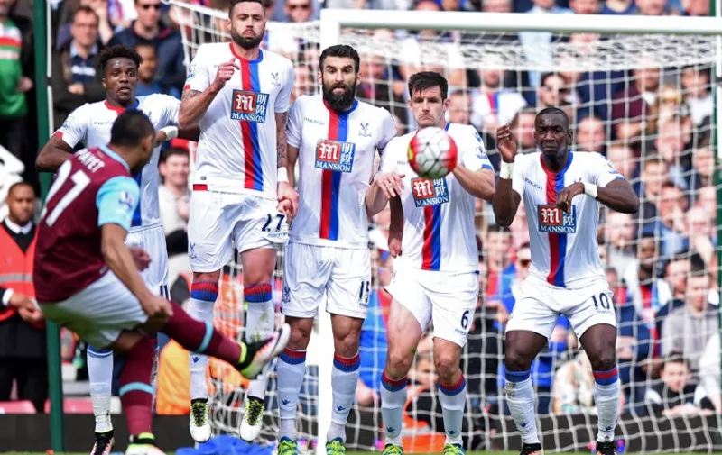 The Crystal Palace wall prepares to jump to block  West Ham United's French midfielder Dimitri Payet's freekick but cannot prevent him scoring their second goal during the English Premier League football match between West Ham United and Crystal Palace at The Boleyn Ground in Upton Park, in east London on April 2, 2016. / AFP / OLLY GREENWOOD / RESTRICTED TO EDITORIAL USE. No use with unauthorized audio, video, data, fixture lists, club/league logos or 'live' services. Online in-match use limited to 75 images, no video emulation. No use in betting, games or single club/league/player publications.  /