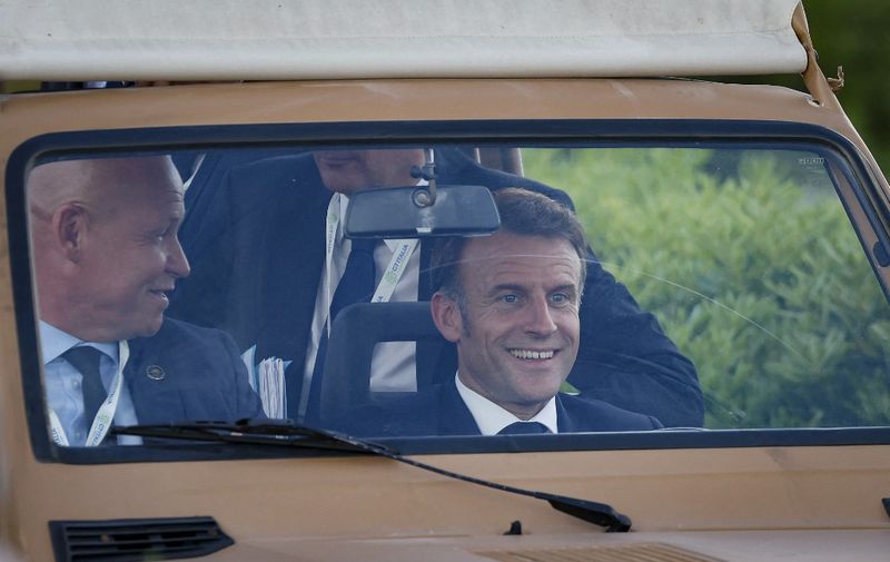 French President Emmanuel Macron (C) drives an electric car during the G7 summit in Fasano, southern Italy, on June 13, 2024. (Photo by Ludovic MARIN / AFP)