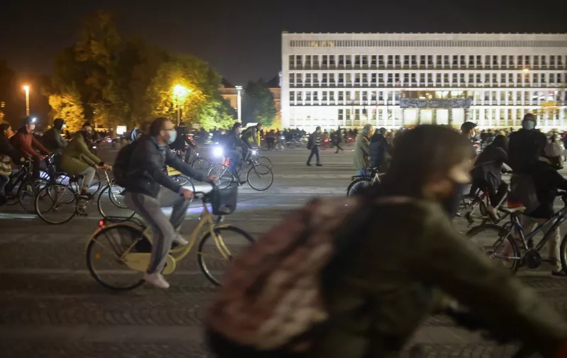 People wearing face masks ride their bikes during an anti-government protest in Ljubljana, Slovenia, on October 9, 2020. (Photo by Jure Makovec / AFP)