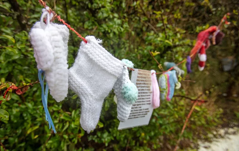 Baby socks and hearts are pictured at a shrine in Tuam, County Galway in January 13, 2021, erected in memory of up to 800 children who were allegedly buried at the site of the former home for unmarried mothers run by nuns. - Irish prime minister Micheal Martin on Wednesday formally apologised for the treatment of unmarried women and their babies in state and church-run homes, where thousands of children died over decades. Some 9,000 children died in Ireland's "mother and baby homes", where unmarried mothers were routinely separated from their infant offspring, according to an official report published Tuesday. (Photo by Paul Faith / AFP)