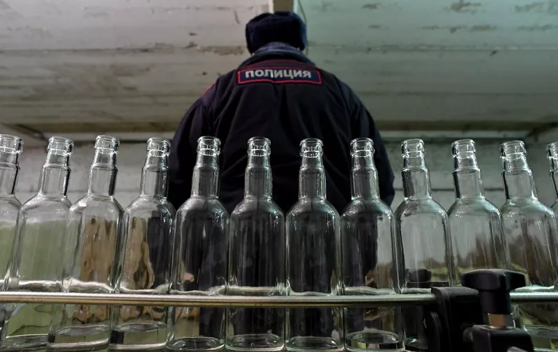 A picture taken on November 25, 2016 shows a policeman as he stands inside of an illicit vodka distillery in the village of Kuchki outside Moscow. - In a snowy field outside Moscow, an abandoned barn conceals an illicit vodka distillery that produces thousands of bottles of Russia's national drink for the black market. In a recent raid, police seized more than 100,000 half-litre vodka bottles with counterfeit labels and tax stamps from the barn, located in the village of Kuchki some 100 kilometres north of the Russian capital. (Photo by Kirill KUDRYAVTSEV / AFP)