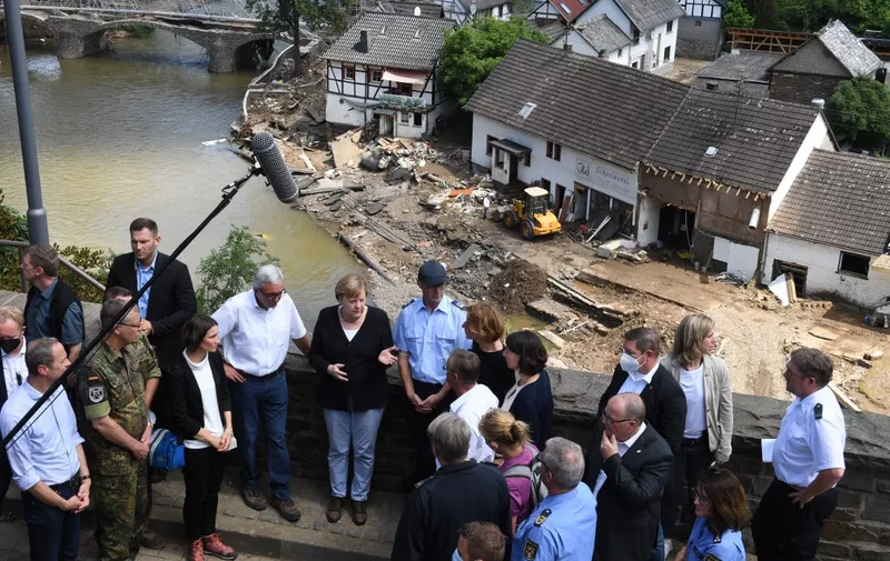 German Chancellor Angela Merkel (C-L) and Rhineland-Palatinate State Premier Malu Dreyer (C-R) speak to people as they stand a bridge during their visit in the flood-ravaged areas, in Schuld near Bad Neuenahr-Ahrweiler, Rhineland-Palatinate state, western Germany, on July 18, 2021. - After days of extreme downpours causing devastating floods in Germany and other parts of western Europe which have been described as a "catastrophe", a "war zone" and "unprecedented", the death toll has risen to 156 in Germany, police said July 18, bringing the total to at least 183 fatalities from the disaster in western Europe. (Photo by Christof STACHE / various sources / AFP)