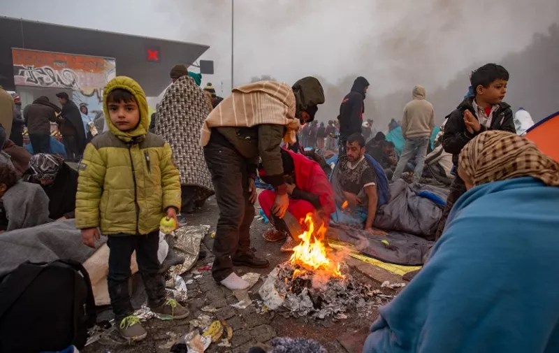 Migrants and refugees try to warm up as they wait for buses in Sentilj to cross the Slovenian-Austrian border into Spielfeld in Austria on October 24, 2015. Around 7,000 migrants have crossed into Austria from Slovenia since October 22, with some 4,500 still stranded at Spielfeld early on October, police said  AFP PHOTO / RENE GOMOLJ