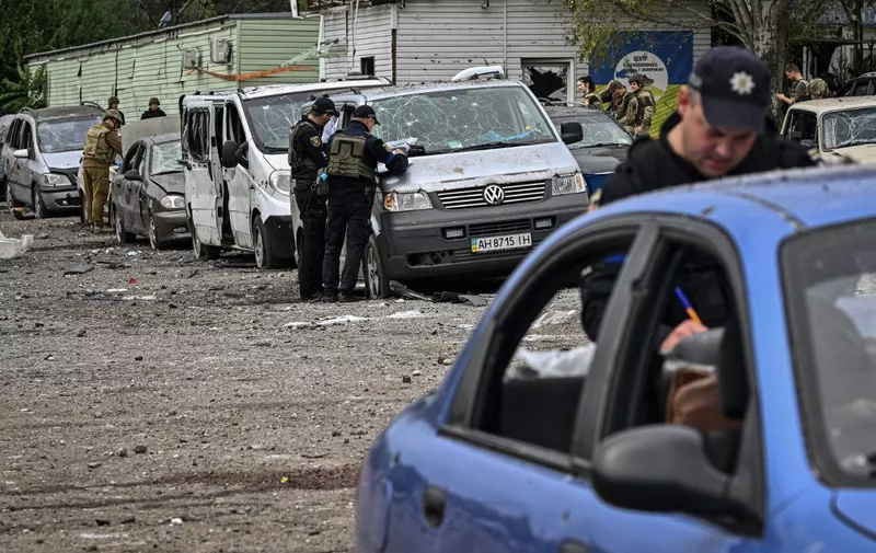 EDITORS NOTE: Graphic content / Ukrainian policemen check cars damaged by a missile strike on a road near Zaporizhzhia on September 30, 2022, amid the Russian invasion of Ukraine. - Ukraine on September 30, blamed Moscow for shelling a convoy of civilian cars in the southern Zaporizhzhia region that killed at least 25 near the front line. (Photo by Genya SAVILOV / AFP)