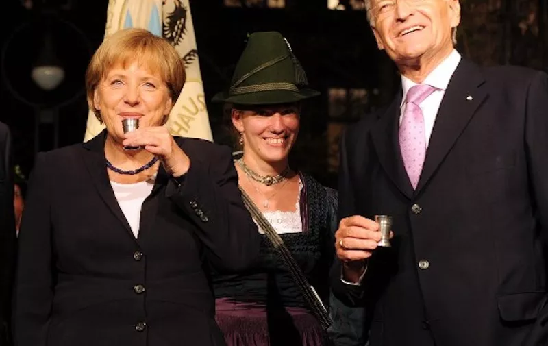 German Chancellor Angela Merkel (C) drinks a schnapps beside President of the European Commission Emanuel Barroso (L) and former Bavarian State Governor Edmund Stoiber (R) ahead OF a ceremony for Edmund Stoiber on the occasion of his 70th birthday in Munich, southern Germany, on September 28, 2011.  AFP PHOTO/CHRISTOF STACHE (Photo by CHRISTOF STACHE / AFP)