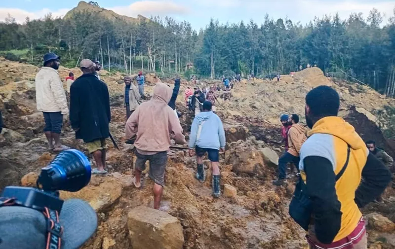 People gather at the site of a landslide in Maip Mulitaka in Papua New Guinea's Enga Province on May 24, 2024. Local officials and aid groups said a massive landslide struck a village in Papua New Guinea's highlands on May 24, with many feared dead. (Photo by AFP)