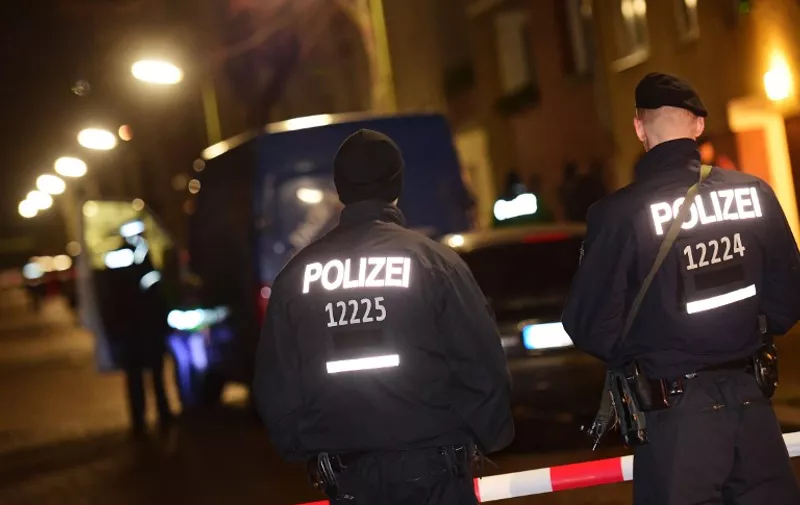 Armed police stand guard as others search a van at the scene in the Karl-Elsasser Street in Berlin's southern suburb of Britz on November 26, 2015. German police detained two suspects in a series of raids targeting Islamists in Berlin and said they were examining a "suspicious object". The raids, involving special forces police, targeted first an Islamic cultural centre in western Charlottenburg district, and then a building in Britz. AFP PHOTO / JOHN MACDOUGALL / AFP / JOHN MACDOUGALL