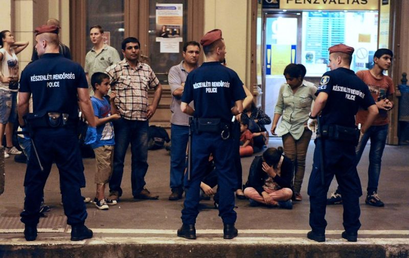 TOPSHOTS
Migrants wait on a platform of the Eastern (Keleti) railway station of Budapest behind of a line of the local police on August 31, 2015, as the last train left in direction of Austria and Germany. Several trains carrying hundreds of migrants arrived in Vienna from Budapest in the evening  of August 31, police said, after they had been stopped at the Austrian border for several hours.  The EU is grappling with an unprecedented influx of people fleeing war, repression and poverty in what the bloc has described as its worst refugee crisis in 50 years. AFP PHOTO / ATTILA KISBENEDEK