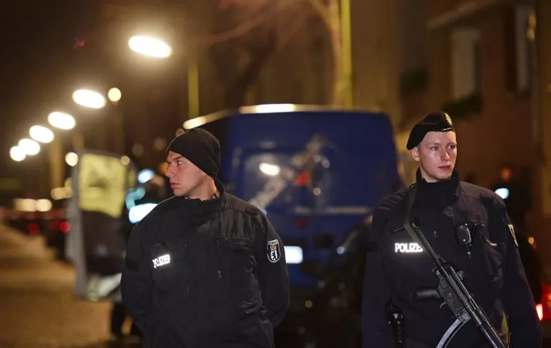 Armed police stand guard as others search a van at the scene in the Karl-Elsasser Street in Berlin's southern suburb of Britz on November 26, 2015. German police detained two suspects in a series of raids targeting Islamists in Berlin and said they were examining a "suspicious object". The raids, involving special forces police, targeted first an Islamic cultural centre in western Charlottenburg district, and then a building in Britz. AFP PHOTO / JOHN MACDOUGALL / AFP / JOHN MACDOUGALL