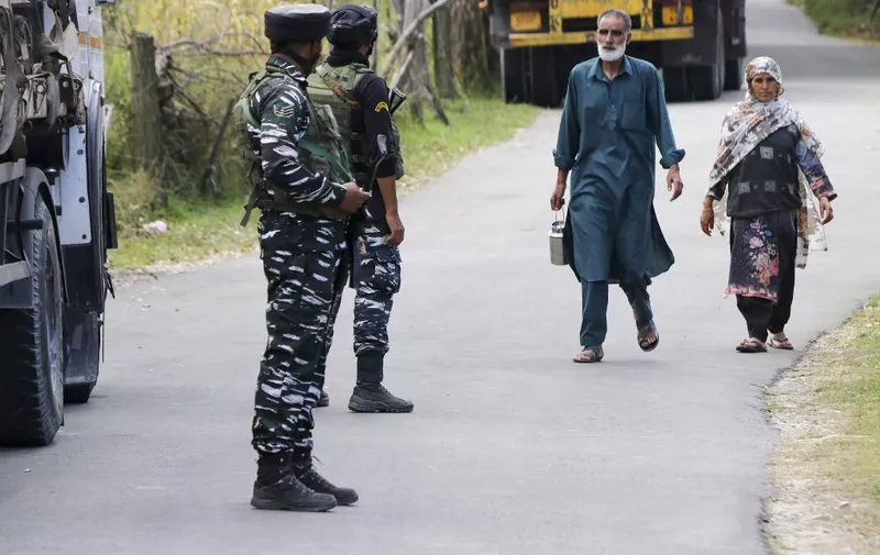 Indian army soldiers stand guard as a Kashmiri family walks past the Gadole forest of Kokernag in south Kashmir's Anantnag district on September 16, 2023. Five Indian officers and two suspected rebels were killed in separate gun battles this week in Indian-administered Kashmir, with clashes ongoing, officials in the disputed region said. (Photo by AFP)