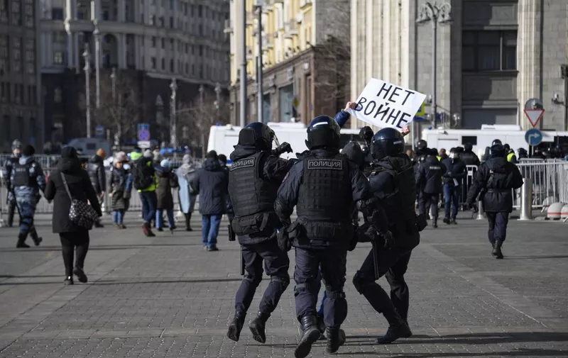 Police officers detain a man holding a placard reading "No to war" during a protest against Russian military action in Ukraine, in Manezhnaya Square in central Moscow on March 13, 2022. (Photo by AFP)