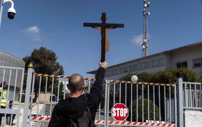A Cypriot demonstrator raises a large cross at the entrance of the Cyprus Broadcasting Corporation (RIK) headquarters in the capital Nicosia on March 6, 2021, during a protest against the controversial Eurovision Song Contest entry "El Diablo" by a Greek singer representing Cyprus. - The song "El Diablo" (Spanish for the devil), performed by Greek singer Elena Tsagrinou, has faced criticism since its release last week.
The Holy Synod, the Cyprus Orthodox Church's highest decision-making body, said the song "essentially praises the fatalistic submission of humans to the devil's authority". (Photo by Iakovos Hatzistavrou / AFP)