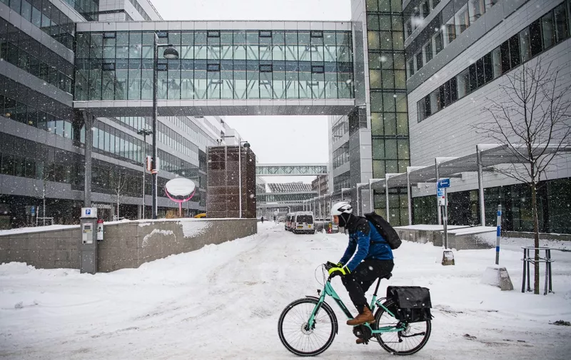 A man rides his bike outside Karolinska Hospital during a snow blizzard on January 14, 2021 in Solna, near Stockholm. (Photo by Jonathan NACKSTRAND / AFP)