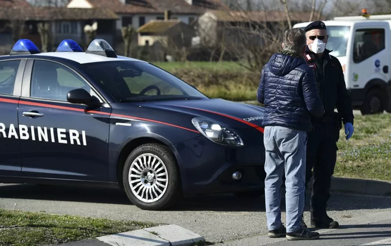 An Italian Carabinieri talks with an inhabitant wearing a respiratory mask at a police check-point few kilometers from the small town of Castiglione d'Adda, southeast of Milan, on February 24, 2020. - Under the shadow of a new coronavirus outbreak, Italy took drastic containment steps as worldwide fears over the epidemic spiralled. (Photo by Miguel MEDINA / AFP)