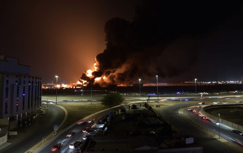 Cars drive on the roads as smoke and flames rise from a Saudi Aramco oil facility in Saudi Arabia's Red Sea coastal city of Jeddah, on March 25, 2022, following a reported Yemeni rebels attack. - Yemeni rebels said they attacked a Saudi Aramco oil facility in Jeddah as part of a wave of drone and missile assaults today as a huge cloud of smoke was seen near the Formula One venue in the city. (Photo by AFP)