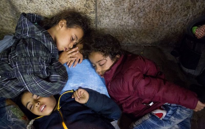 Refugee children rest as they wait to get on a train from Gyor to Hegyeshalom in Hungary on September 19, 2015. During the night they were transported from the Croatian border in buses organised by the Hungarian authorities. Hungary has finished placing barbed wire along 41 kilometres (25 miles) of its border with Croatia in a bid to stem a flow of migrants from that country, a defence ministry spokesman said. AFP PHOTO / VLADIMIR SIMICEK