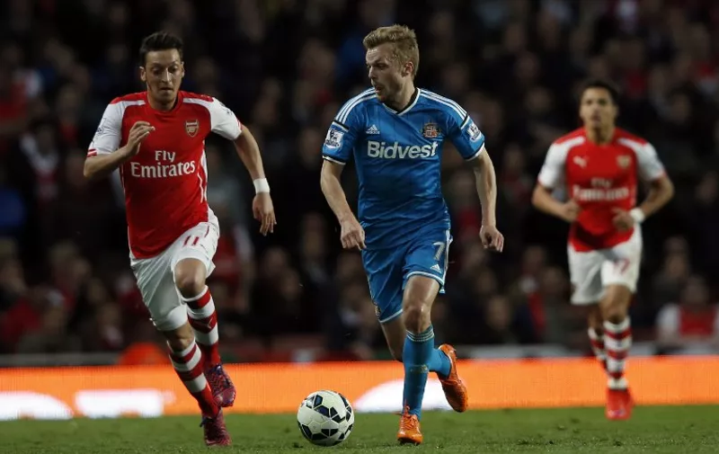 Sunderland's Swedish midfielder Sebastian Larsson (C) runs away from Arsenal's German midfielder Mesut Ozil (L) during the English Premier League football match between Arsenal and Sunderland at the Emirates Stadium in London on May 20, 2015. Sunderland held Arsenal to a 0-0 draw earning the Black Cats a valuable point that ensures their Premier League survival. AFP PHOTO / ADRIAN DENNIS

RESTRICTED TO EDITORIAL USE. NO USE WITH UNAUTHORIZED AUDIO, VIDEO, DATA, FIXTURE LISTS, CLUB/LEAGUE LOGOS OR LIVE SERVICES. ONLINE IN-MATCH USE LIMITED TO 45 IMAGES, NO VIDEO EMULATION. NO USE IN BETTING, GAMES OR SINGLE CLUB/LEAGUE/PLAYER PUBLICATIONS.