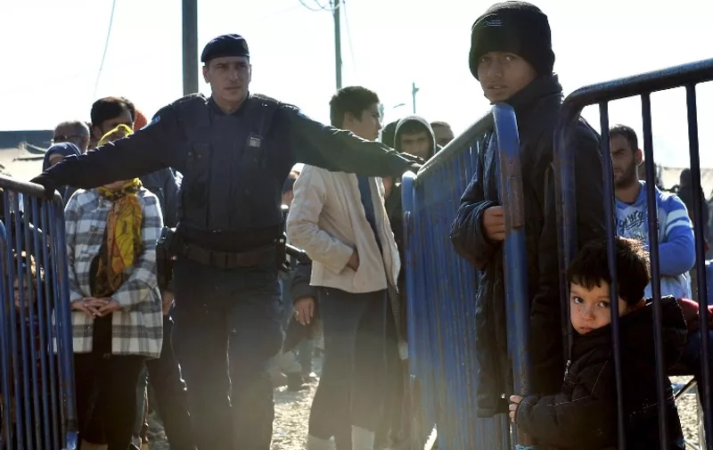 A Croatian policeman stands guard as migrants and refugees queue to enter a transit camp in Slavonski Brod on November 4, 2015. Thousands of newly arrived migrants and asylum seekers are on the move through Croatia and towards the border with Slovenia, from where they plan to continue their journey to western European countries. Thousands -- many fleeing violence in Syria, Iraq and Afghanistan -- have been making their way from Turkey to the Balkans in recent months, hoping to reach Germany, Sweden and other EU states. AFP PHOTO / ELVIS BARUKCIC