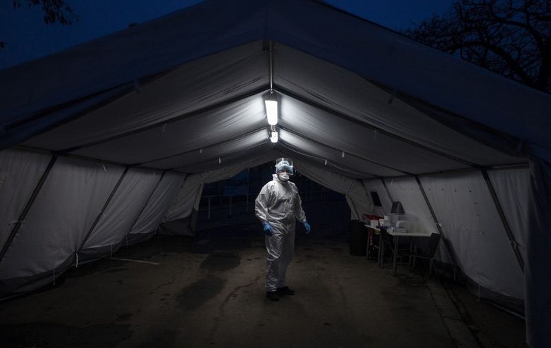 A medical worker wearing protective equipment waits for a client at the drive-in coronavirus testing station on February 23, 2021 in Prague. (Photo by Michal Cizek / AFP)