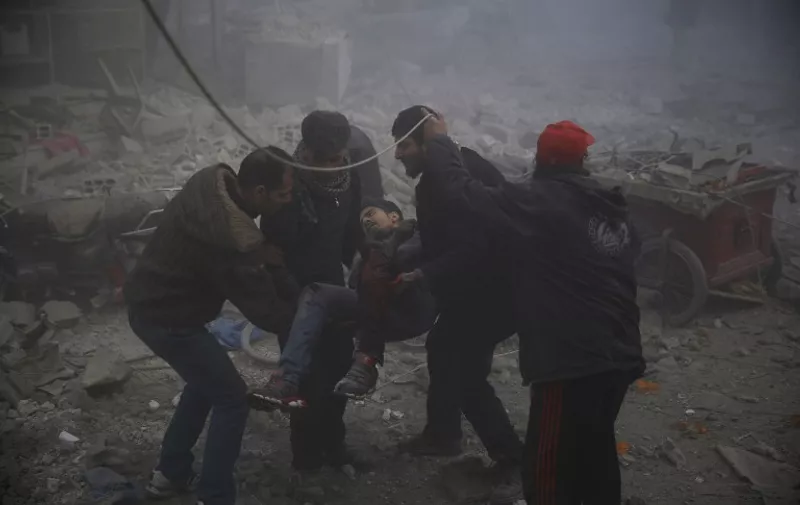 Men evacuate a wounded civilian following reported airstrikes on the town of Hamouria in the eastern Ghouta region, a rebel stronghold east of the Syrian capital Damascus, on December 9, 2015. The Syrian Observatory for Human Rights reported at least 11 civilians, including four children, were killed in strikes on the town of Hamouria, but said it was unclear if they were carried out by Russian or regime aircraft. 
 / AFP / SAMEER AL-DOUMY