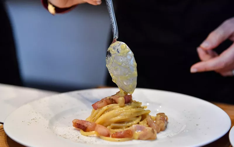 One of the chefs of the traditional team prepares the traditional famous Italian pasta dish "spaghetti alla carbonara", during a preview for the press on April 5, 2019, one day before the international event Carbonara Day (#CarbonaraDay) in Rome. - The preview consists of three teams of cooking students challenge each other with modified Carbonara dishes, a traditional one, a vegan one and an experimental one. (Photo by Andreas SOLARO / AFP)