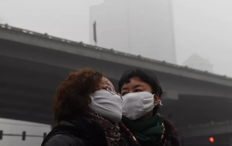 Two women wear masks on a heavily polluted day in Beijing on December 1, 2015. China has ordered thousands of factories to shut as it grapples with swathes of choking smog that were nearly 24 times safe levels on December 1, casting a shadow over the country's participation in Paris climate talks. A thick grey haze shrouded Beijing, with the concentration of PM 2.5, harmful microscopic particles that penetrate deep into the lungs, climbing as high as 598 micrograms per cubic metre. AFP PHOTO / GREG BAKER / AFP / GREG BAKER