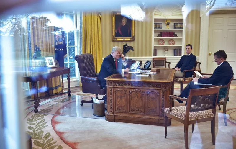 US President Donald Trump(L)seen through an Oval Office window speaks on the phone to King Salman of Saudi Arabia, watched by Senior Advisor Jared Kusher(C), and National Security Michael Flynn, in the Oval Office of the White House on January 29, 2017 in Washington, DC. - Trump is to speak by phone with the leaders of Saudi Arabia and the United Arab Emirates on January 29, 2017, amid an uproar over his travel ban for some Muslim majority countries. Trump also will talk to the acting president of South Korea, Hwang Kyo-Ahn, the White House said Saturday in a brief statement. (Photo by MANDEL NGAN / AFP)