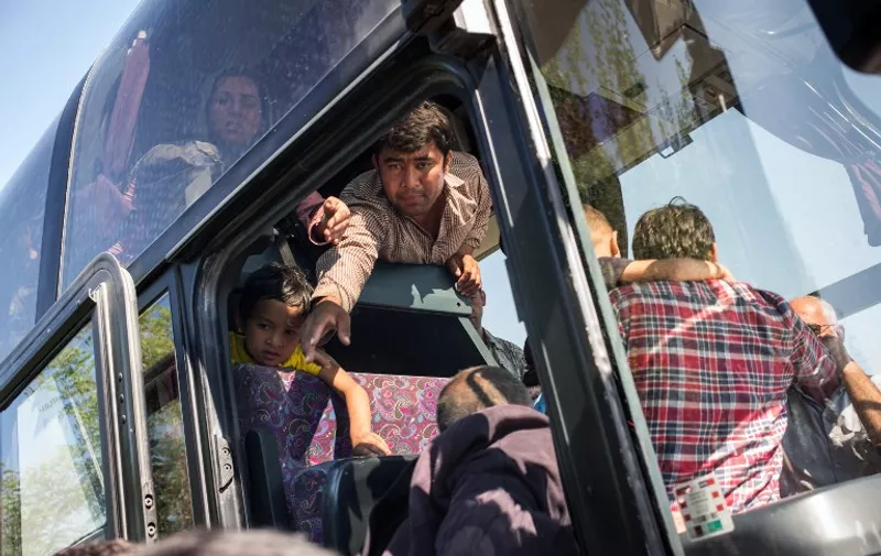 A man tries to help members of his family onto a waiting bus that will take them to Opatovac transit camp not far from the Croatian village of Bapska, on September 23, 2015. About a thousand migrants crossed the border between Serbia and Croatia this morning, and were later transported to a transit camp in Opatovac, about 20 kilometers away. AFP PHOTO/FEDERICO SCOPPA