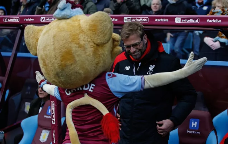Liverpool's German manager Jurgen Klopp reacts as he gets a hug from the Aston Villa mascot ahead of the English Premier League football match between Aston Villa and Liverpool at Villa Park in Birmingham, central England on February 14, 2016. / AFP / ADRIAN DENNIS / RESTRICTED TO EDITORIAL USE. No use with unauthorized audio, video, data, fixture lists, club/league logos or 'live' services. Online in-match use limited to 75 images, no video emulation. No use in betting, games or single club/league/player publications.  /