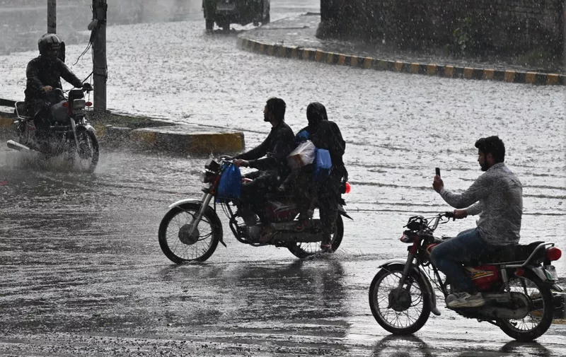 Motorcyclists ride motorbikes along a street during a rainfall in Lahore on June 6, 2023. (Photo by Arif ALI / AFP)