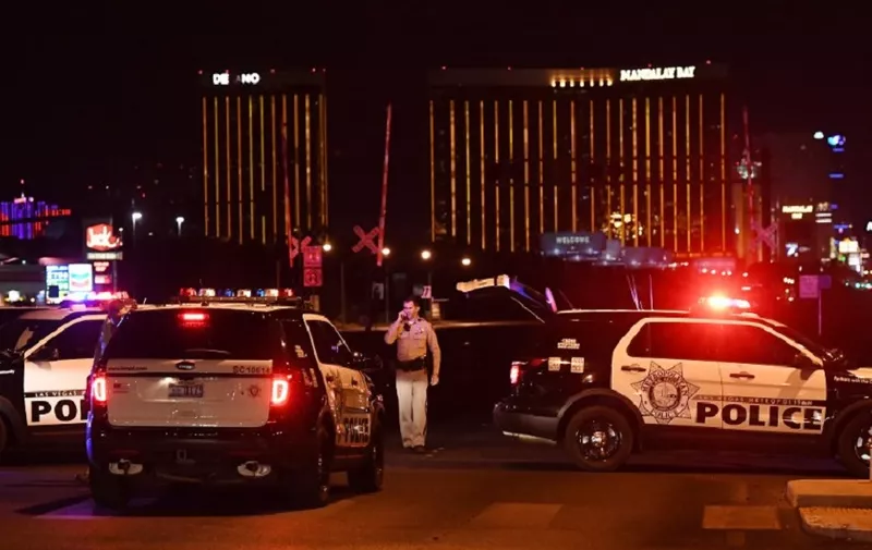 EDITORS NOTE: Graphic content / Police form a perimeter around the road leading to the Mandalay Hotel (background) after a gunman killed at least 50 people and wounded more than 200 others when he opened fire on a country music concert in Las Vegas, Nevada on October 2, 2017. 
Police said the gunman, a 64-year-old local resident named as Stephen Paddock, had been killed after a SWAT team responded to reports of multiple gunfire from the 32nd floor of the Mandalay Bay, a hotel-casino next to the concert venue. / AFP PHOTO / Mark RALSTON