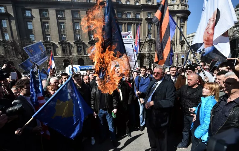 Serbian nationalist politician Vojislav Seselj surrounded by his supporters holds a burning NATO flag during an anti-government rally on March 24, 2015, in front of the building of the former federal Interior Ministry in Belgrade, which was destroyed during the 1999 NATO air campaign against Serbia and Montenegro. AFP PHOTO / ANDREJ ISAKOVIC / AFP / ANDREJ ISAKOVIC