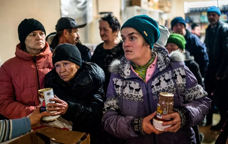 Local residents receive food at a humanitarian aid centre in Bakhmut, Donetsk region, on January 6, 2023, as the Russia-Ukraine war enters its 316th day. - Russia and Ukraine have both suffered heavy casualties in the fight for Bakhmut, and most of the city's pre-war population of 70,000 have left for safer territory, leaving behind cratered roads and buildings reduced to rubble and twisted metal. (Photo by Dimitar DILKOFF / AFP)
