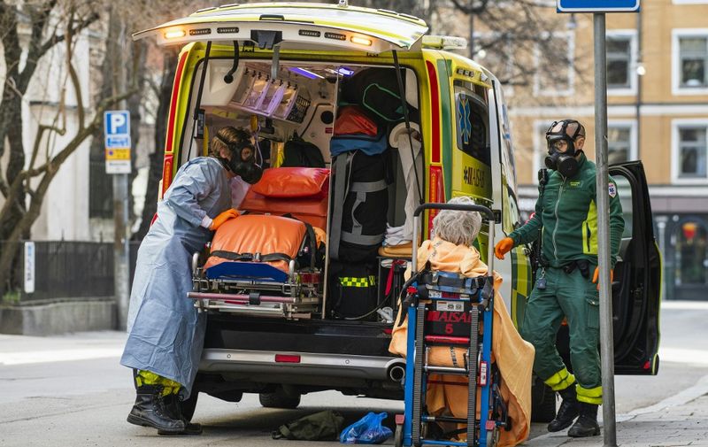 Paramedics with protective gas masks help to transport a patient on April 6, 2020 in Stockholm, during the novel coronavirus Covid-19 pandemic. (Photo by Jonathan NACKSTRAND / AFP)