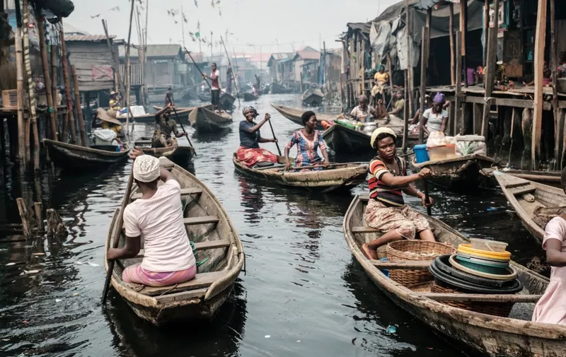 A picture taken on March 2, 2019 shows people taking boats on a waterway  in the Makoko waterfront community in a polluted lagoon in Lagos, Africas biggest megalopolis in Nigeria. - The sprawling community began in the 19th century as a fishing village for immigrants who settled on the water's edge. As more arrived and land became rare, people started to move out onto the water. Over time, Makoko became a floating realm of perhaps a quarter of a million people, although the real number is anyone's guess. (Photo by YASUYOSHI CHIBA / AFP)