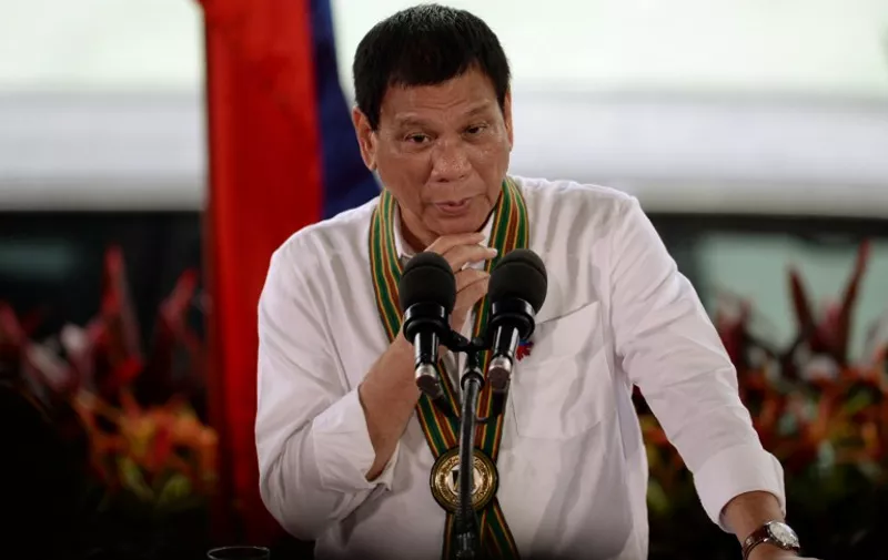 This photo taken on October 4, 2016 shows Philippine President Rodrigo Duterte gesturing as he delivers a speech during a "Talk to the Troops" visit to army personnel in Manila. 
Duterte's popularity has soared during his first three months in office, an independent survey showed on October 6, in an apparent endorsement by Filipinos of his brutal crime crackdown. / AFP PHOTO / TED ALJIBE